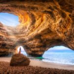 Woman alone under the sunlight in the natural Sea Cave of Benagil, Algarve, Portugal