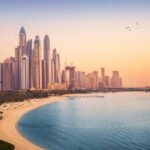 Sunset view of the Dubai Marina and JBR area and the famous Ferris Wheel and golden sand beaches in the Persian Gulf. Holidays and vacations in the UAE