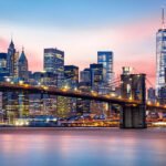 Brooklyn Bridge at and the Lower Manhattan skyline under a purple sunset