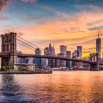 New York City Skyline on the East River with Brooklyn Bridge at sunset.